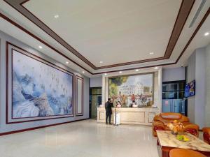 a man standing in a room with a large painting on the wall at Vienna Hote Nanjing Lishui Tianshengqiao Avenue Wuxiang Shuizhen 5 0 in Lishui