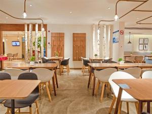 a dining room with wooden tables and chairs at Kyriad Marvelous Hotel Shanghai Daning International Plaza in Shanghai