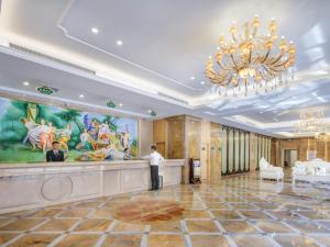 晋江市にあるVienna International Hotel Fujian Quanzhou Jinjiang Airportのホテルロビーのカウンターに立つ男