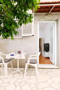 a patio with a white table and chairs and a television at Apartman Žuvela in Vela Luka