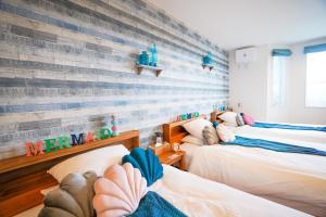 a bedroom with three beds and a wooden wall at Hotel Santa Barbara Miyakojima Resort in Miyako-jima
