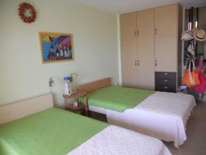 sypialnia z 2 łóżkami z zieloną i białą pościelą w obiekcie Most Astonishing Sunset w mieście Vráchos