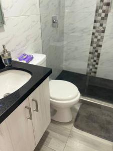 y baño con aseo, lavabo y ducha. en Luxury Corferias-USA Embassy & Airport Condominium, en Bogotá