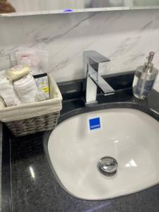 lavabo en el baño con una cesta de artículos de aseo en la encimera en Luxury Corferias-USA Embassy & Airport Condominium, en Bogotá