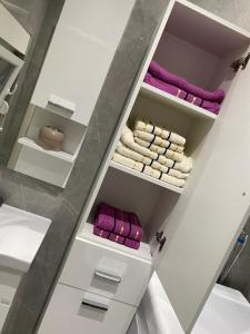 a walk in closet with white shelves and purple towels at Apartmani Vasković in Trebinje