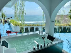 a bathroom with a tub with a view of the ocean at Morabito Art Cliff in Uluwatu