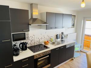 a kitchen with black cabinets and a sink at Bergluft Appartement - Haus Lerchegger in Mössna