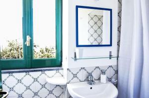 baño con lavabo, espejo y ventana en Casa Tiberio, en Massa Lubrense