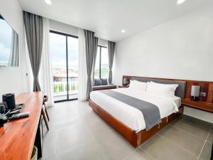 a bedroom with a bed and a desk and windows at Emerald Residence Kampot in Kampot