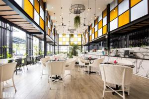 ein Restaurant mit weißen Tischen, Stühlen und Fenstern in der Unterkunft Blue Lagoon Hotel in Chiang Rai