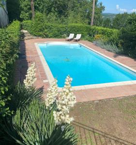 a swimming pool in a yard with two chairs and flowers at Le Chevalier Noir in Cordes-sur-Ciel