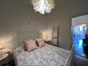 Schlafzimmer mit einem Bett mit rosa Kissen und einem Kronleuchter in der Unterkunft Celena House Kitries in Avía