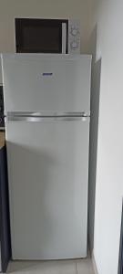 einen weißen Kühlschrank in einer Küche mit offener Tür in der Unterkunft Le Chant des Vagues in Audinghen