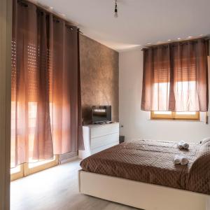 a bedroom with a bed and a tv and windows at Monfalcone City Room Rental Apartment in Cagliari