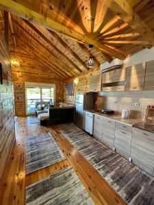 a large kitchen with wooden ceilings and a living room at Cottage Ajna - Ada Bojana in Ulcinj
