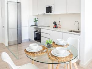 cocina blanca con mesa de cristal y sillas blancas en Apartment Abora with Pool, Gym and Free Parking, en Las Palmas de Gran Canaria
