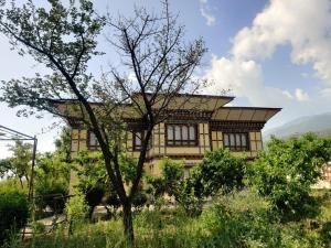 a house on top of a hill with a tree at Nirvana Lodge in Paro