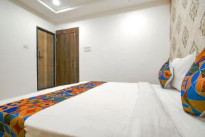 um quarto com uma grande cama branca e uma porta de madeira em FabHotel Ten Eleven em Indore