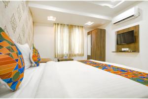 a bedroom with a white bed and a tv at FabHotel Ten Eleven in Indore