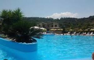 una gran piscina con agua azul y sillas en Casa vacanza DF con piscina en Campofelice di Roccella