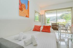 um quarto branco com uma grande cama branca com almofadas laranja em « La Grande Résidence » Vue Mer, Piscine em Menton