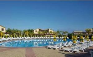 a large swimming pool with white lounge chairs in a resort at Casa vacanza DF con piscina in Campofelice di Roccella