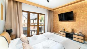 Apartamenty Sun & Snow Green Park في شكلارسكا بوريبا: غرفة نوم بسرير وتلفزيون على جدار