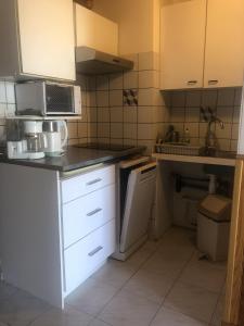 małą kuchnię z białymi szafkami i kuchenką mikrofalową w obiekcie Residence la Catalane w mieście Saint-Cyprien-Plage