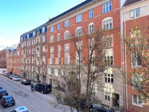 un gran edificio de ladrillo rojo con coches aparcados en una calle en Two Bedroom Apartment In Copenhagen, Brohusgade 16,, en Copenhague