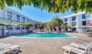 uma piscina com cadeiras e um edifício em Motel 6-Belmont, CA - San Francisco - Redwood City em Belmont