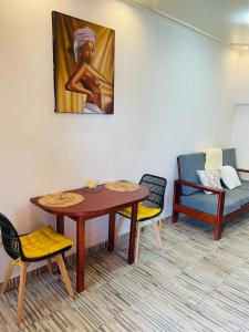 a living room with a table and chairs and a painting at AS Guest House in Libreville