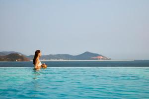 a woman sitting in the water in the ocean at The Shanhaitian Resort Sanya, Autograph Collection in Sanya