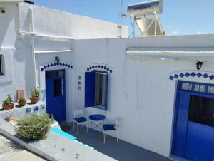 Biały dom z niebieskimi drzwiami i patio w obiekcie Mari...Milo w mieście Péran Triovasálos
