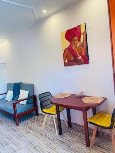 Habitación con mesa, sillas y un cuadro en la pared. en AS Guest House, en Libreville