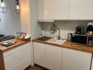 a kitchen with white cabinets and a sink and a microwave at Sosnowe Apartamenty - Marina. in Augustów