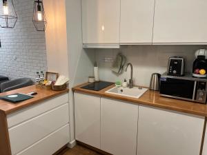 una cucina con mobili bianchi, un lavello e un microonde di Sosnowe Apartamenty - Marina 3 a Augustów