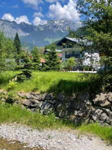 ein grünes Feld mit einem Haus und Bergen im Hintergrund in der Unterkunft Ferienwohnung Top 3 in Lungötz
