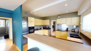a kitchen with white cabinets and a blue wall at Cosy villa with pool near ocean in Labenne