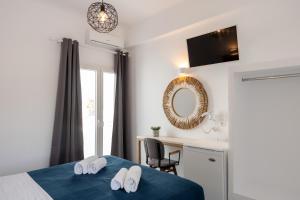 1 dormitorio con cama, escritorio y espejo en Galinos Hotel for adults only, en Parikia