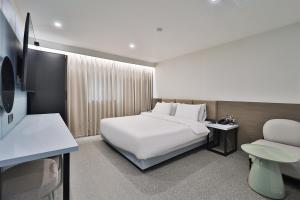 Pokój hotelowy z białym łóżkiem i krzesłem w obiekcie DOAN STAY HOTEL w mieście Ulsan