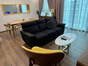 a living room with a black couch and a table at Home Abroad 1 Jazz Suites Vivacity in Kuching
