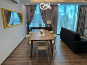 a dining room with a table and chairs and a couch at Home Abroad 1 Jazz Suites Vivacity in Kuching
