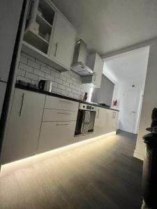 a kitchen with white cabinets and a light on the floor at Cozzzy Seaside Retreat in Mablethorpe