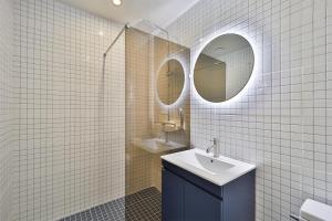 a white tiled bathroom with a sink and two mirrors at DOAN STAY HOTEL in Ulsan