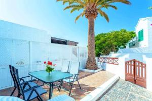 a patio with a table and chairs and a palm tree at Summer Dreams Beach House in Playa Honda