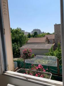 a window with a view of a garden with pink flowers at Chambre privée avec partage des espaces communs in Créteil