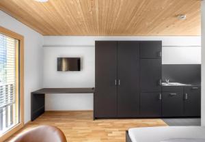 uma cozinha com armários pretos e um lavatório num quarto em Simotel em Aussersiggam