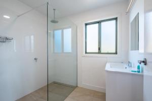 een witte badkamer met een douche en een wastafel bij Silver Moon at Half Moon in Bicheno