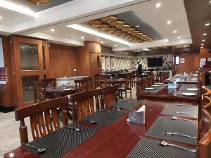 a restaurant with wooden tables and chairs and a laptop at New Gitanjali Hotel, New Digha in Digha
