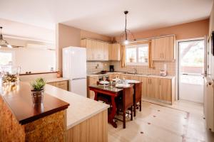 a kitchen with a table and a white refrigerator at Rahes Villa with Private Pool in Zakynthos Town